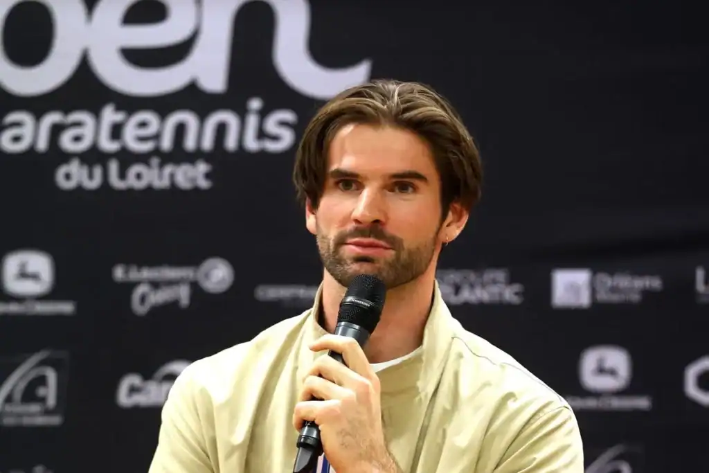 Lucas Mazur, micro en main, lors d'une prise de parole devant le panneau de l'Open de paratennis du Loiret