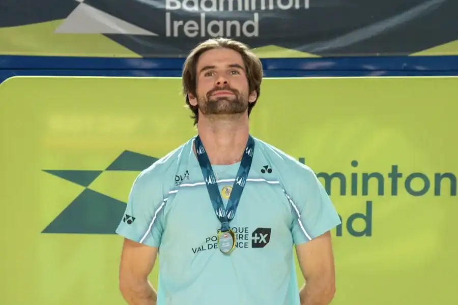 Lucas Mazur, une médaille autour du cou, devant le panneau Badminton Ireland